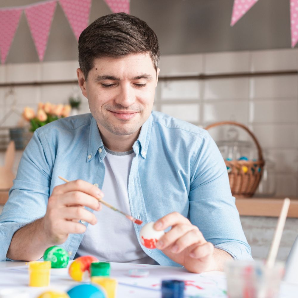 Man painting a small object in a kitchen setting